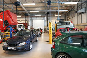 Large motor vehicle workshop with cars on inspection ramps and a lorry