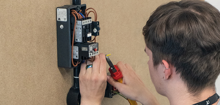 Student strips the end from the yellow wire to join it into a fuse box