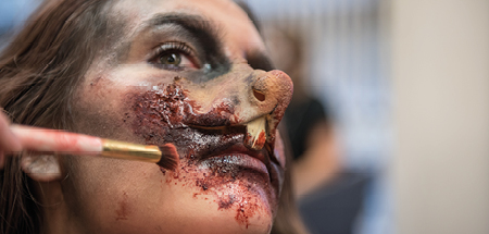 Face with prosthetic mouse nose and teeth with make-up artist using make-up to blend onto the face