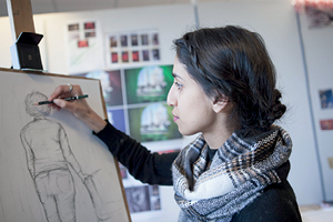 A student works on an easel to draw a portrait