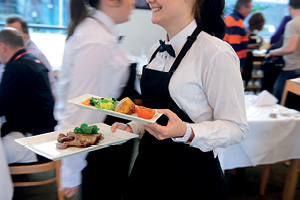 Waiting staff carry plates of food in the busy restaurant