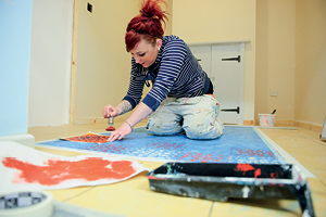 A student uses stencils to paint a floor