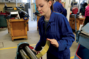A student uses a machine bending sheet metal into a curve