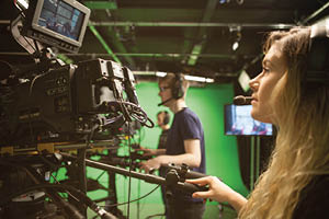 Students use large TV Cameras in a studio with a green screen