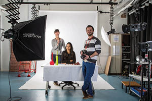 Students in a photography studio set up with backdrop and lighting
