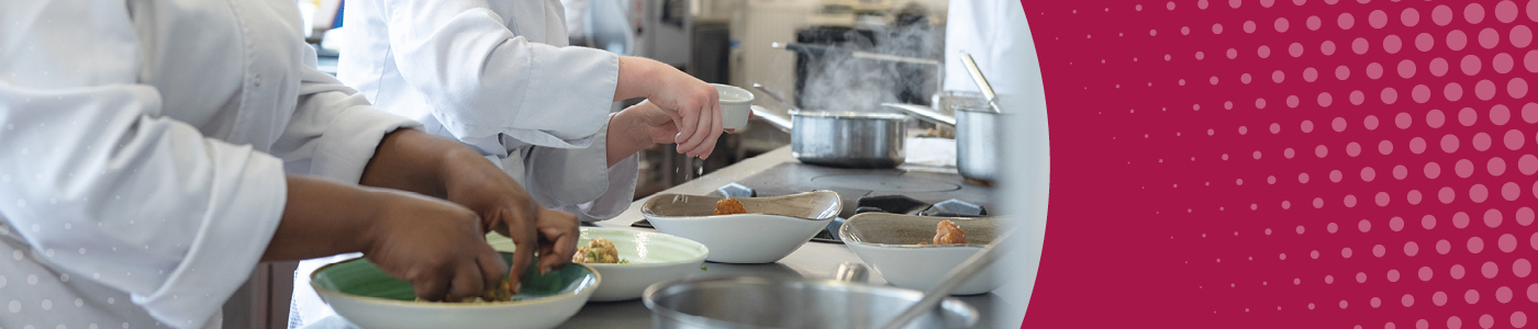 Students in chef’s whites plate up food. In the background you can see saucepans with steam rising from them