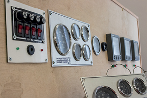 A collection of different boat electrical switches and displays on a wall