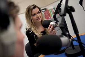 Students inside a studio speak into large microphones