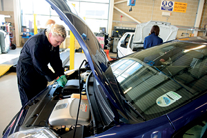 A student works under a car bonnet on the engine
