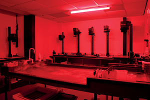 Darkroom with enlargers and developing bench under a red safelight